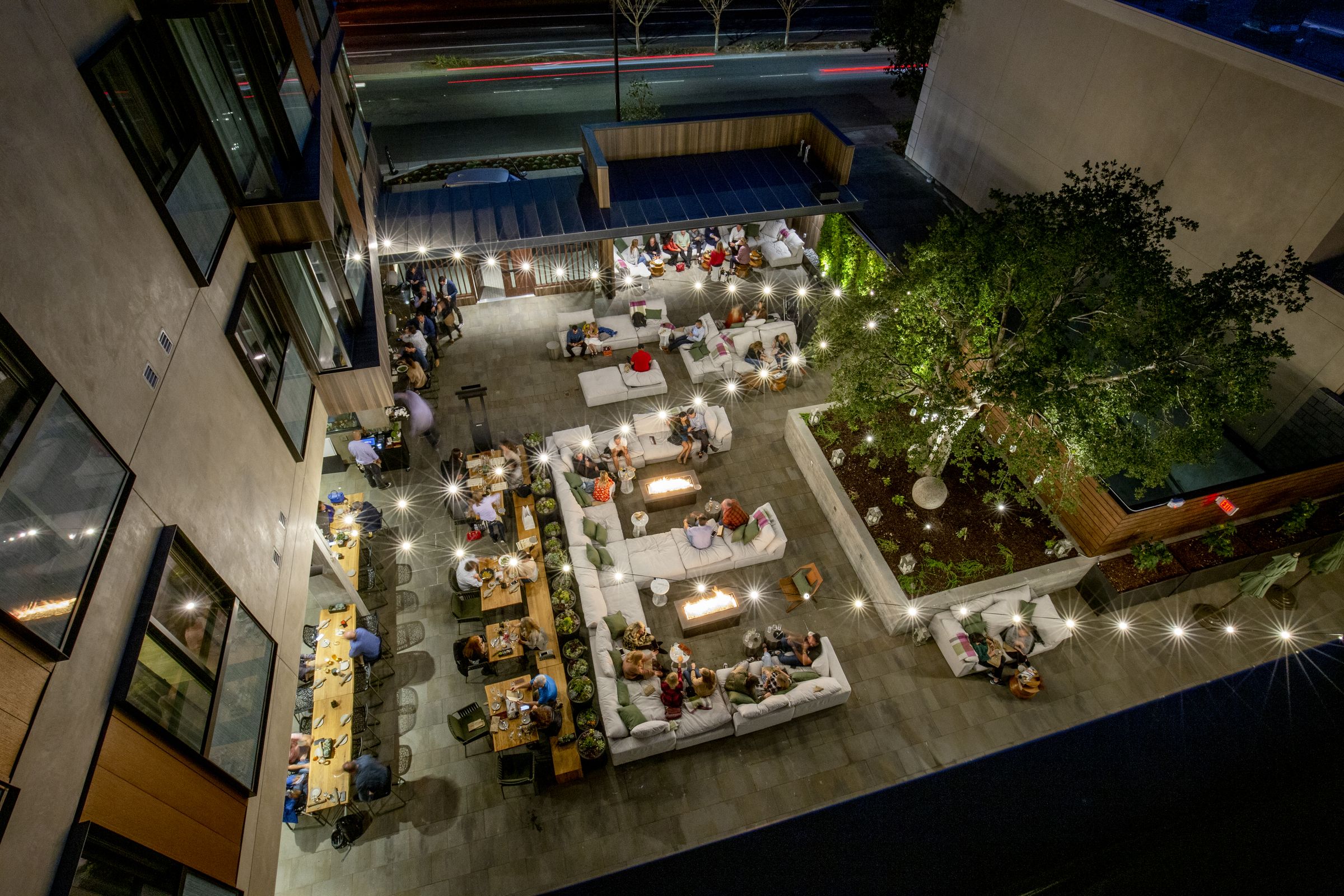 Guests gathered around fire pits and string lights in the evening courtyard at Park James